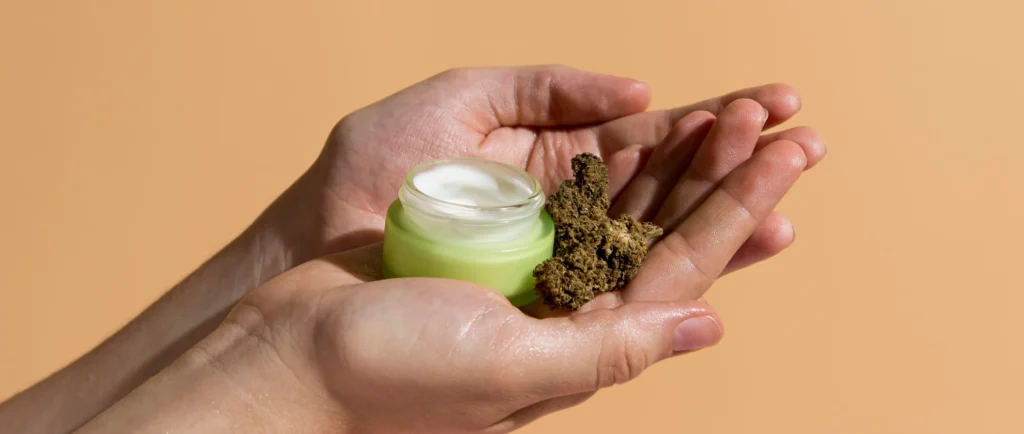 Person holding cannabis cream jar with weed bud