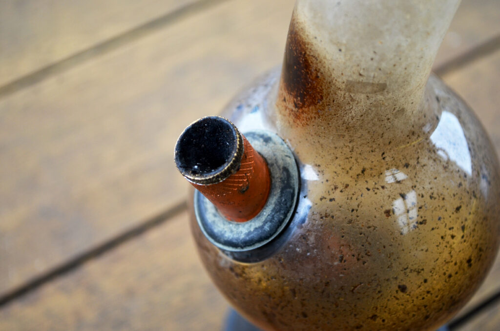 Close-up of used glass bong bowl on wooden surface