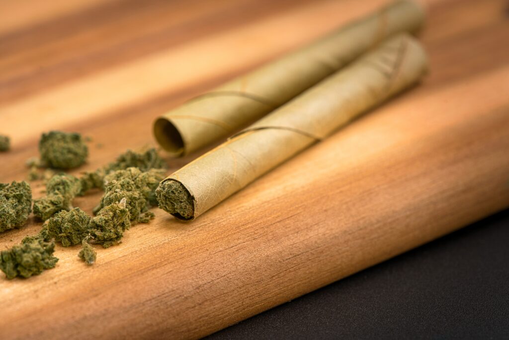 Rolled blunts on a wood table with cannabis