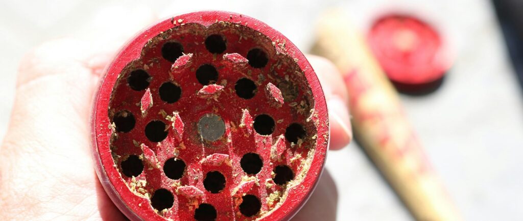 Person holding red weed grinder