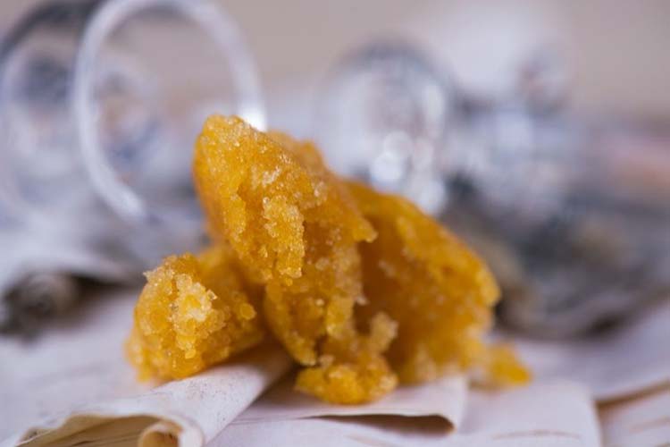 Cannabis crumble concentrate with glass jars in background