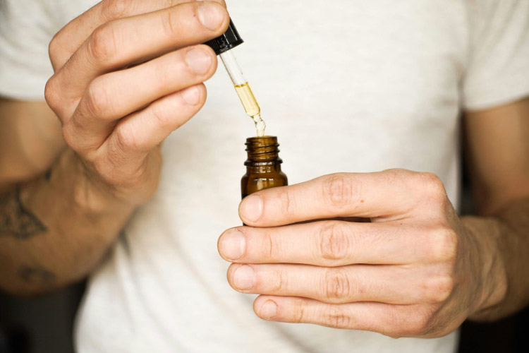 Person using dropper to dispense tincture into bottle