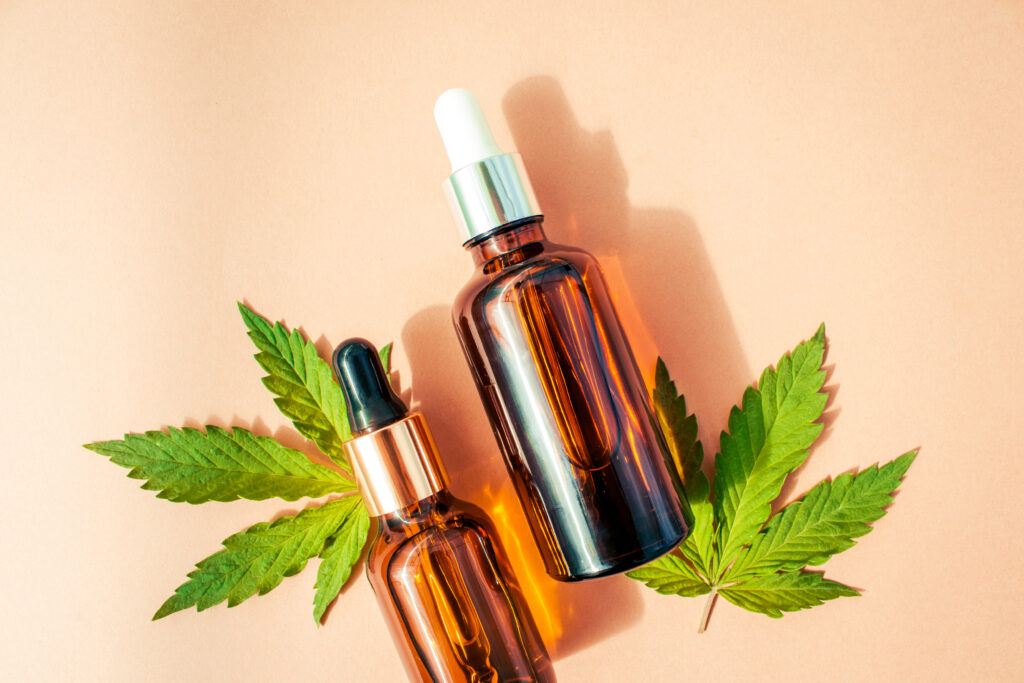 Tincture bottles with cannabis leaves on pastel background