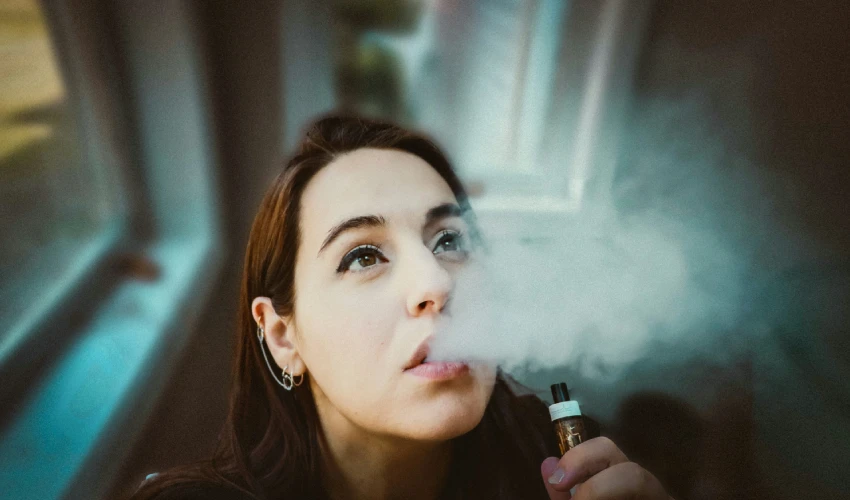 woman-holding-a-black-and-gold-vape-cartridge-while-smoking